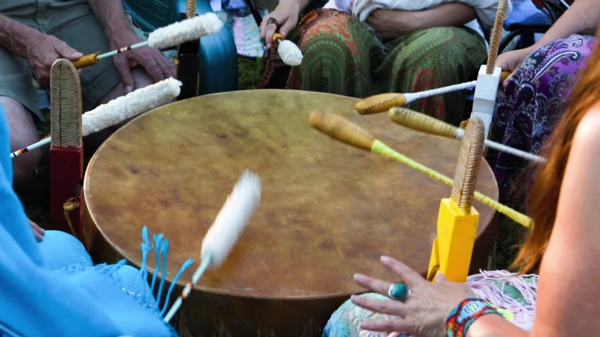 Sacred drums at spiritual singing group. A close up view on a large mystical mother drum as a group of native musicians use traditional beater to perform cultural music outdoors. Royalty-Free Stock Footage #1038496430