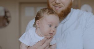 Portrait of a cute caucasian newborn baby hanging on father’s arm. RAW Graded footage 4K slow motion 50fps
