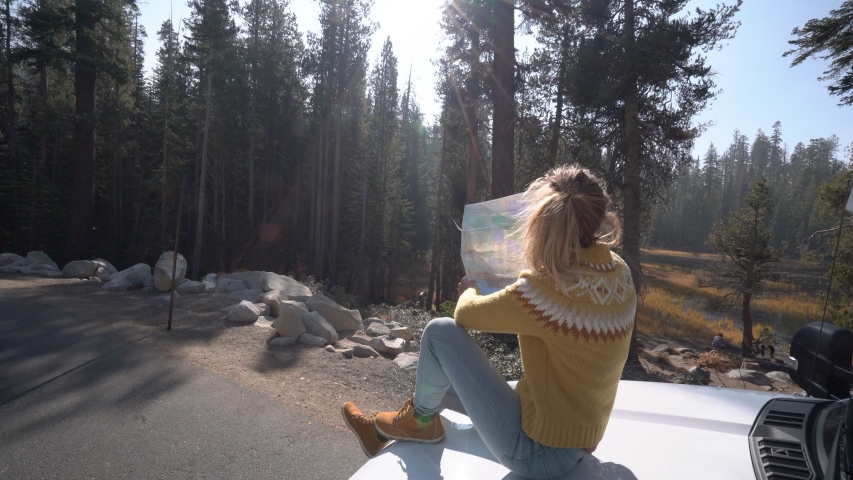 Road trip concept; Woman driving in USA checking at road map for directions