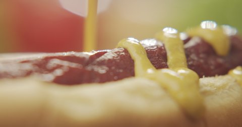 Macro shot of hot dog poured with mustard. 4K Slow Motion