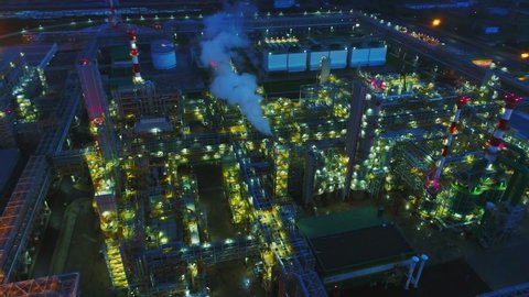 fantastic gas and oil refinery complex illumination with production towers and pipelines in summer evening aerial view