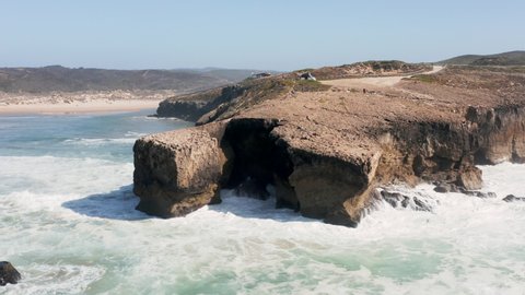 Ocean waves hitting the cliffs near Praia de Monte Clérigo in Portugal
