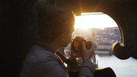 Young girl tourist exploring downtown of Prague. Rear woman with photo camera taking picture from frame arch window of Old Town Bridge Tower, Top view Charles bridge in golden hour - Powered by Shutterstock - Get 15% off with code: PIKWIZARD15