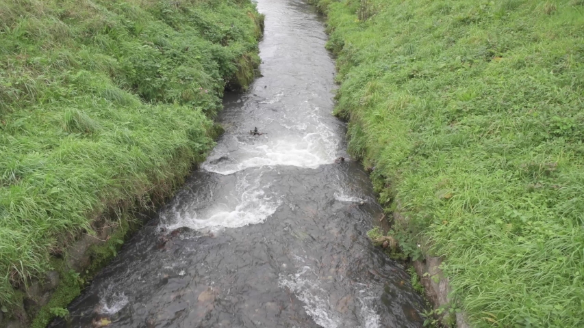 View above fast flowing stream going over rocks making white waves