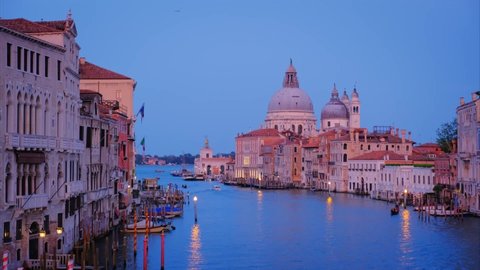 View of Venice Grand Canal with boats and Santa Maria della Salute church in the evening from Ponte dell'Accademia bridge. Venice, Italy. Zoom in effect
