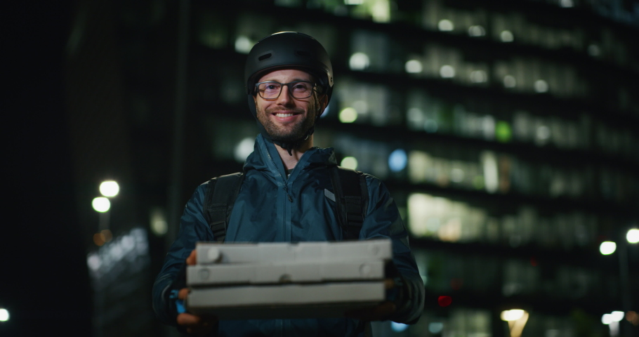 Portrait of an young pizza delivery courier is smiling satisfied with his work in the camera in the evening in a city center. | Shutterstock HD Video #1038524237