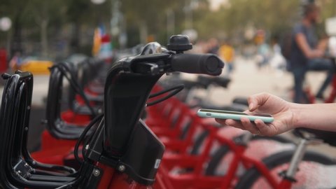 Woman take Electric Kick scooter or bike bicycle in sharing parking lot, tourist phone application. New sharing business project started in city, eco transportation
