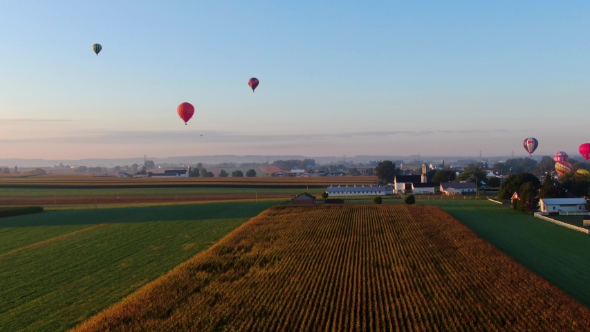 Rising aerial reveals colorful hot air balloon festival in beautiful morning sunlight at Lancaster Pennsylvania, inflate and take-off