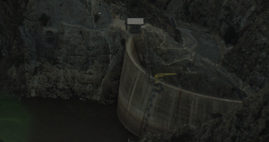 Helicopter aerial shot of massive dam between mountains, drone