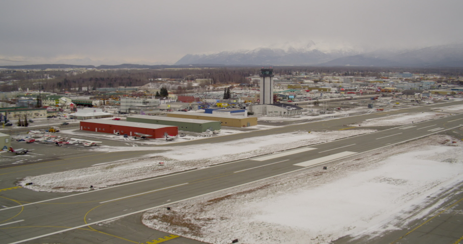 Aerial helicopter shot, flying over colorful winter town, airfield, restaurants, trucks and cars pass below, drone footage