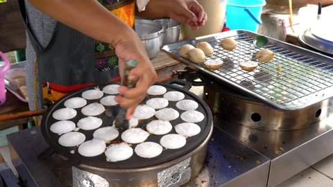 Taking kanom krok cakes out of mold tray and placing them on cooling rack