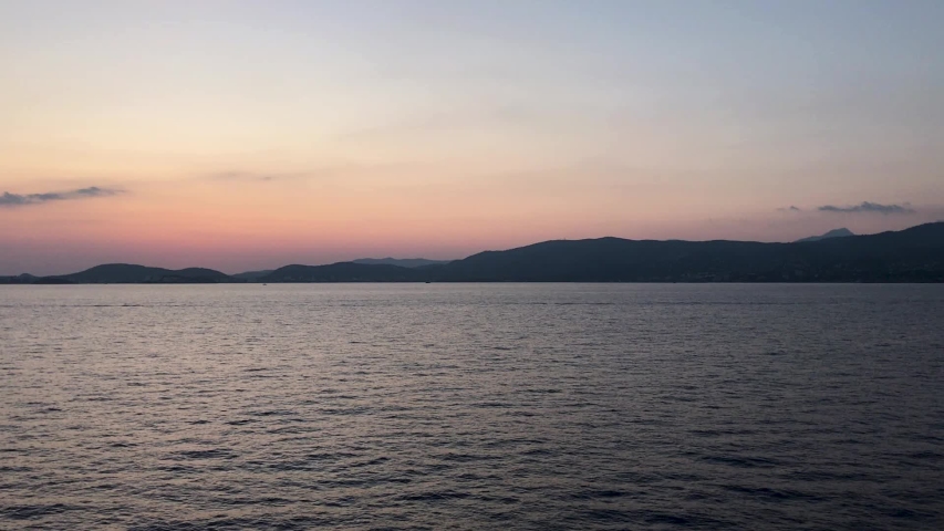 Coast of Spain. Spanish coastline near Barcelona, Mallorca, and Palma. Passing in the water as the sun sets over the mountain coastline.