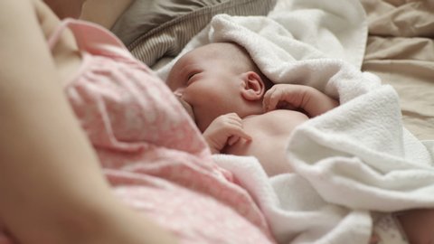 Woman breastfeeding newborn baby. Mother breastfeeding newborn boy lying in bed. Concept breast feeding. Baby eating mother's milk. Young woman nursing and feeding baby. Concept of lactation infant.