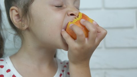 Portrait of a baby eating peach. Close-up little girl eating nectarine.
