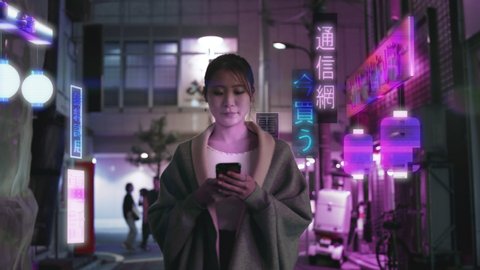 Japanese woman in future Augmented Reality Tokyo city looks at her phone with holographic ads in the background that read: Phone, Telecom, High tech, Buy Now, Network, Security, and Free to try.  