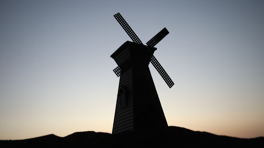 Windmill silhouette standing on hill against the sunset sky. Selective focus