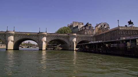 PARIS, FRANCE - APRIL 2019: Pan shot right to left on the boat floating on the Seine river near Pont Neuf in Paris in spring during calm sunny weather.