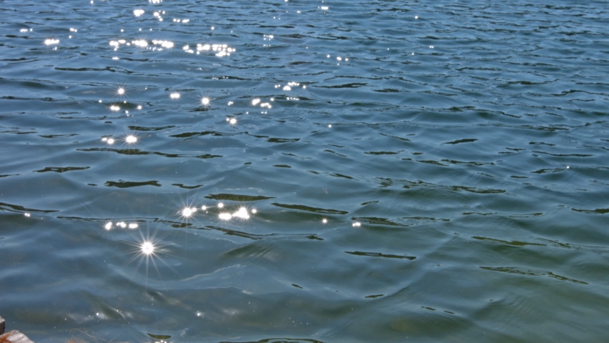 Slow motion pan reveal redhead woman sleeping on a dock by the water in a turquoise dress