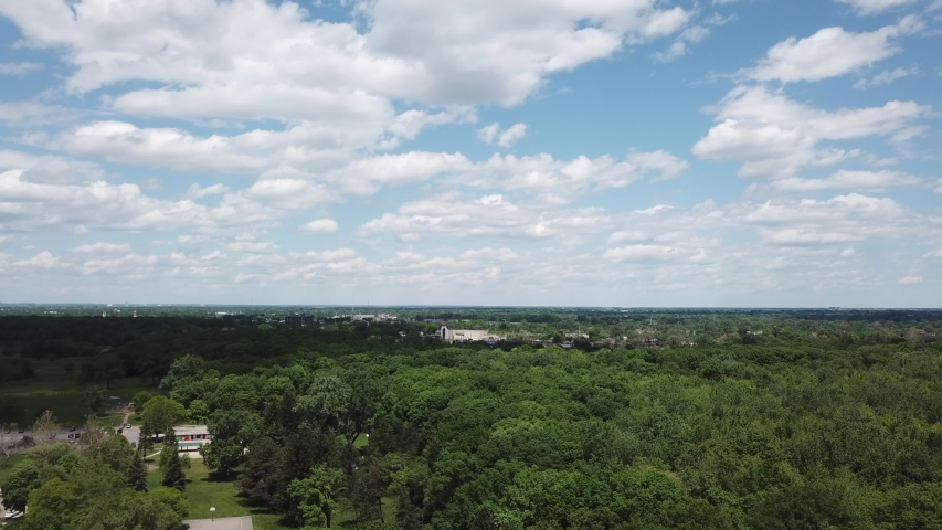 Aerial Drone Footage of Woodward Ave and Palmer Park. Detroit Skyline on a beautiful sunny day. Public transportation, and people walking by on the city streets. 