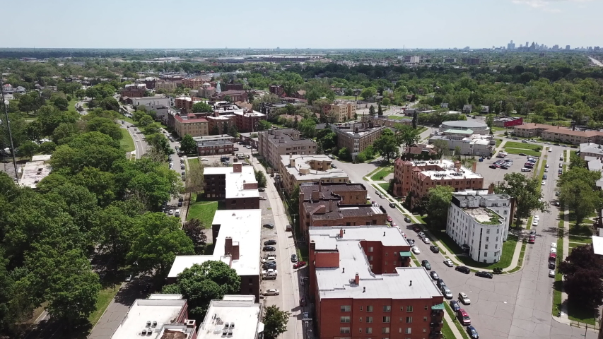 Aerial Drone Footage of Woodward Ave and Palmer Park. Detroit Skyline on a beautiful sunny day. Public transportation, and people walking by on the city streets. 