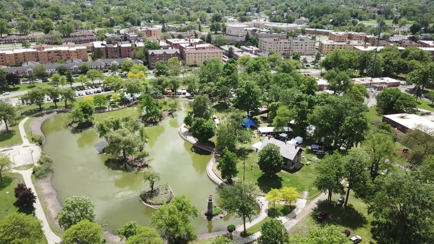 Aerial Drone Footage of Woodward Ave and Palmer Park. Detroit Skyline on a beautiful sunny day. Public transportation, and people walking by on the city streets. 