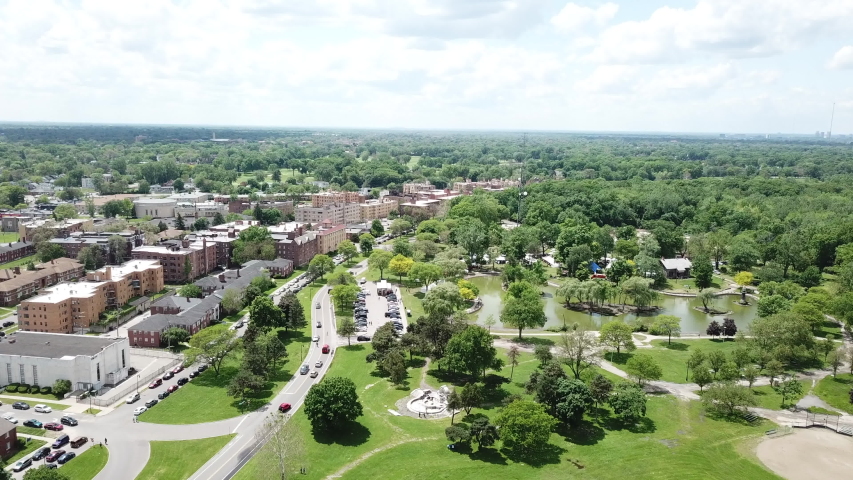 Aerial Drone Footage of Woodward Ave and Palmer Park. Detroit Skyline on a beautiful sunny day. Public transportation, and people walking by on the city streets. 