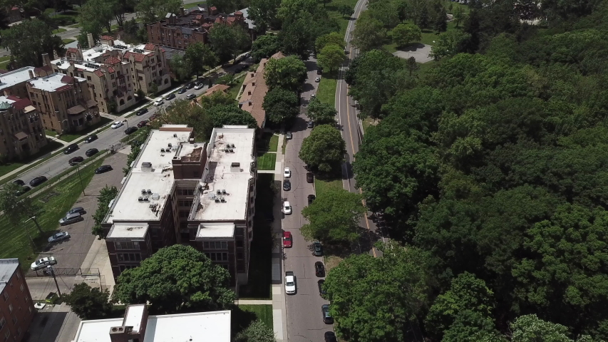 Aerial Drone Footage of Woodward Ave and Palmer Park. Detroit Skyline on a beautiful sunny day. Public transportation, and people walking by on the city streets. 