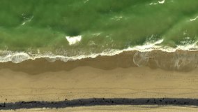 Static aerial shot waves crashing on the sand drone footage