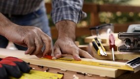 Craftsman adult carpenter with a pencil and the carpenter’s square trace the cutting line on a wooden table. Construction industry, housework do it yourself. Footage.