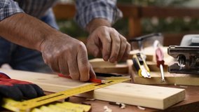 Craftsman adult carpenter with a pencil and the carpenter’s square trace the cutting line on a wooden table. Construction industry, housework do it yourself. Footage.