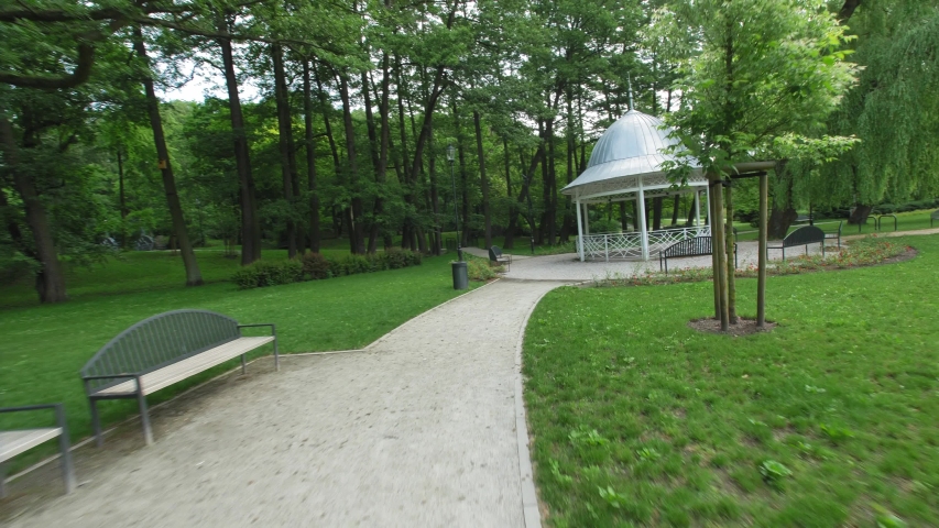 Camera Flying along Park Alleys Trees Benches and Arbor