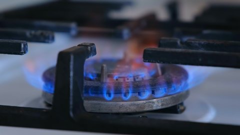 Natural gas inflammation in stove burner. Gas burning from a kitchen gas stove. Close-up side view flame. Gas for cooking food at home.