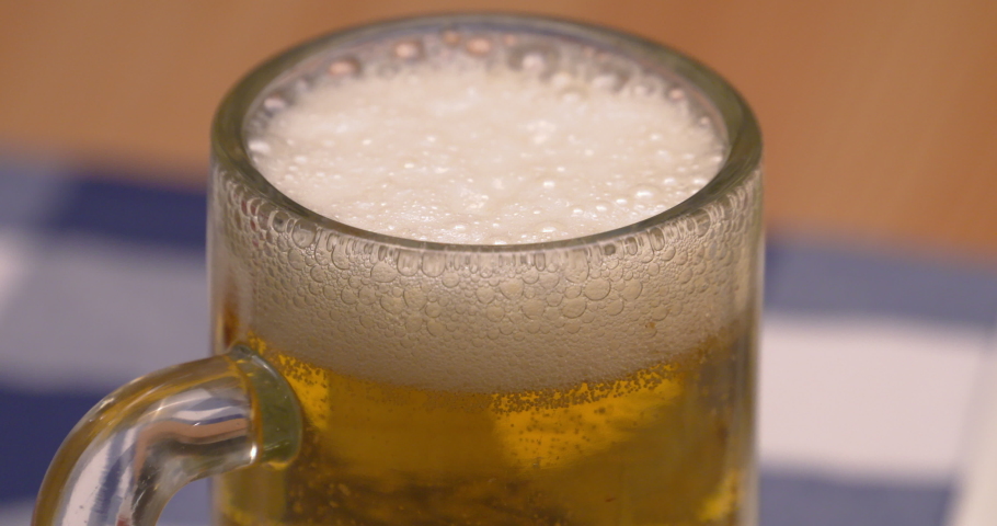 Freshly poured, ice cold beer with foaming head in a beer mug.