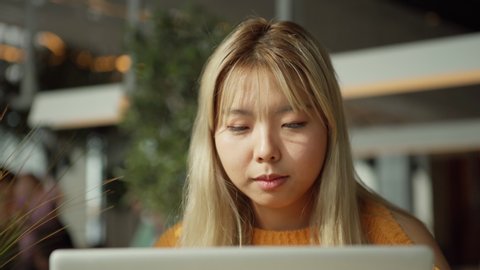 Dreamy ethnic lady closing laptop and looking away while sitting in restaurant and studying Stockvideo