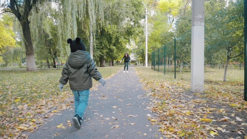 Happy baby boy running in autumnal park. Little child playing on autumn walk. Autumnal forest with golden leaves. Steadicam video, 4K slow motion.