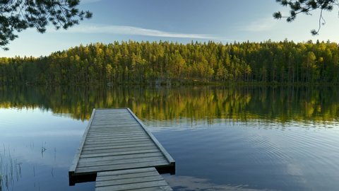 Pier in Repovesi national park, Kouvola, Finland. Steadicam shot of pier and lake with reflections at sunset. 4K, UHD Stockvideo