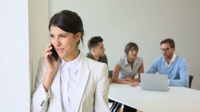 Businesswoman talking on phone, team in background