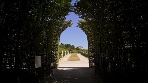 VERSAILLES, FRANCE - APRIL 2019: Tracking shot of coming into Versailles gardens with statues going out of alleys with bushes