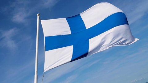 Finland flag with flag pole in super slow motion with beautiful summer sunny sky as background. Medium shot