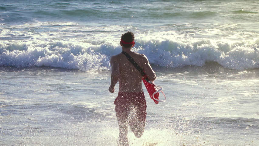 Male lifeguard running along the beach Royalty-Free Stock Footage #1038600557