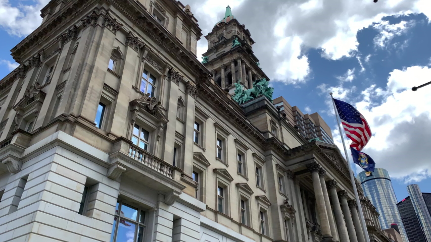 Aerial Drone Footage of Woodward Ave Detroit. Detroit skyline and traffic visible on a beautiful sunny day. Public transportation, and people walking by on the city streets.