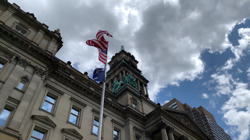 Aerial Drone Footage of Woodward Ave Detroit. Detroit skyline and traffic visible on a beautiful sunny day. Public transportation, and people walking by on the city streets.