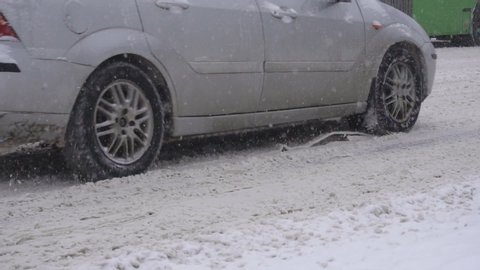 Cars and vehicles ride on a snowy road in the city, reagents clearing the road in winter, background, slow motion, close-up