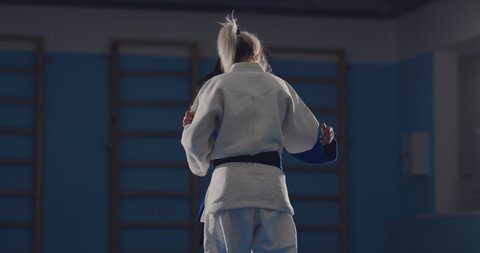 Girls show judo techniques, tatami wrestling. Sparing young women in the gym.