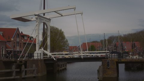 Real time footage of traditional Dutch canal drawbridge raising opening to allow a pleasure boat through then closing, filmed in the historic Dutch town of Enkhuizen in North Holland the Netherlands