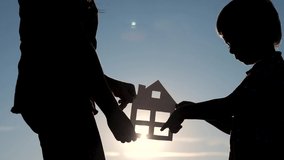 happy family construction house teamwork concept . Mom a and son holding home paper house in his hands at sunset silhouette sunlight . life lifestyle symbol ecology video . boy and girl hold paper