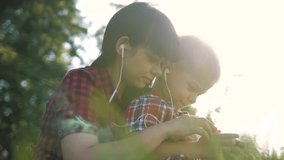 happy family funny video slow motion play music teamwork outdoors. Mom and son listen lifestyle to music on smartphone in the same headphones for two. happy family mother woman and son little boy