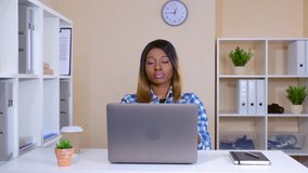 young cheerful businesswoman dancing in the office. happy woman sitting at the workplace watching video on laptop and have fun at work