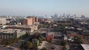 Aerial Drone Footage of Woodward Ave. Detroit museums, church, skyline and traffic visible on a beautiful sunny day. Public transportation, and people walking by on the city streets.