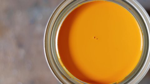 A hand stirring yellow paint with a peace of plastic in a metal container. Can of paint. Mixing a can of paint.